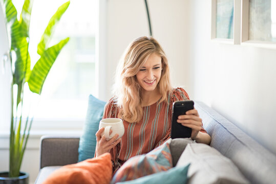 Happy woman in apartment smiling at smart phone