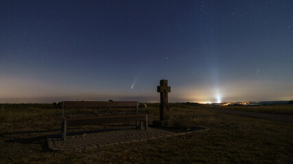 The Neowise comet in the night sky with resting bench and stone way cross with air base Spangdahlem...