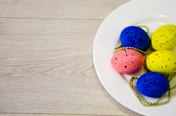 colorful eggs for Easter that lie on a white plate and light with sparkles