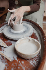 close up hand modeling pottery on a potter wheel in a cozy home workshop. Creating products from environmentally friendly clay with their own hands. Aesthetically beautiful female hands of the artist