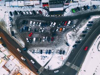 Top down aerial view of small parking place near supermarket in small european city at winter sunny evening