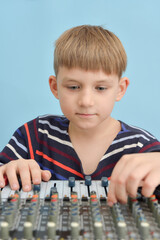 A boy controls a mixing console in a music studio.