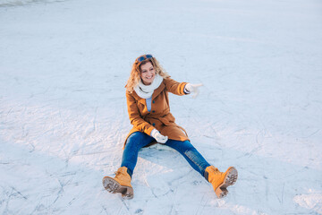 Fototapeta na wymiar woman sitting in the snow. Woman is having fun outside in the snow. Woman with brown coat on a frozen lake . Be active despite the cold outside. Enjoy winter