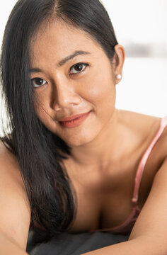 Beautiful Thai woman posing in rose pink night dress on bed