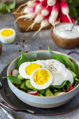 Fresh spring food, healthy vegan lunch bowl. Spinach, cucumber, radish salad and boiled eggs with sour cream.