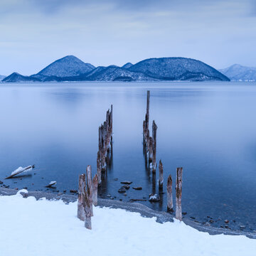 Long exposure shot of wooden sticks in the water at lake Toya, Hokkaido, Japan