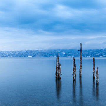 Long exposure shot of wooden sticks in the water at lake Toya, Hokkaido, Japan