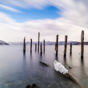Long exposure shot of wooden sticks in the water at lake Toya, Hokkaido, Japan