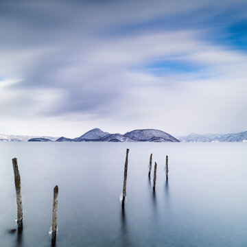 Long exposure shot of wooden sticks in the water at lake Toya, Hokkaido, Japan