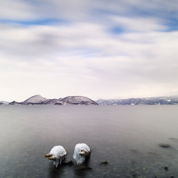 Long exposure shot of logs covered in ice at lake Toya, Hokkaido, Japan
