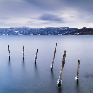 Long exposure shot of wooden sticks in the water at lake Toya, Hokkaido, Japan