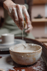 Close-up aesthetically beautiful hand survive sponge to handle pottery on a pottery wheel Creating mugs of eco-friendly clay with their hands in a cozy home workshop