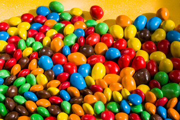 Fototapeta na wymiar M&M's candy on the yellow background, colorful candy, multicolored gradient