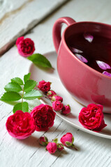 cup of tea and rose flowers and buds on white wood