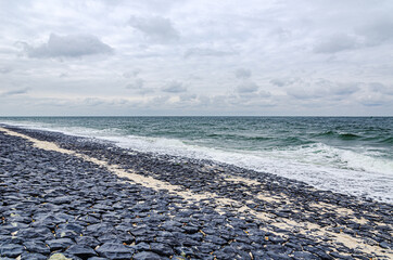Bank revetment with basalt columns to protect the shore from the surf of the sea waves, Sylt,...