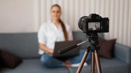 Woman blogger recording video indoors, selective focus on camera display. Space for text