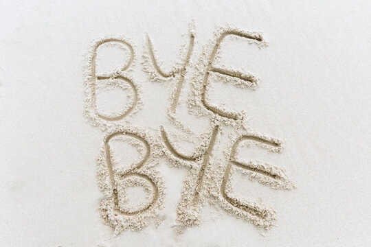 Bye Bye written in sand on white beach