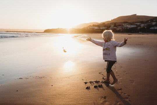 Young Girl throwing sand at the beach at Sunset in Australia