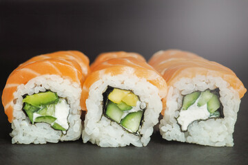 Close up philadelphia roll sushi with salmon, cucumber, avocado, cream cheese. Sushi menu. Japanese food on black background
