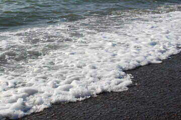 waves with foam break on the beach shore on the Black Sea