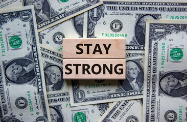 Stay strong symbol. Wooden blocks with words 'stay strong'. Beautiful background from dollar bills. Copy space. Motivational, business and stay strong concept. Copy space.