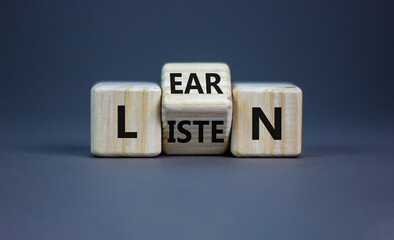 Listen and learn symbol. Turned a wooden cube and changed the word 'listen' to 'learn'. Beautiful grey background, copy space. Business, education and listen and learn concept.