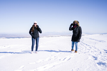 Two attractive women walking in the snow in thermal clothing.
