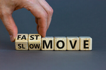 Time to fast move symbol. Businessman turns a wooden cube and changes words 'slow move' to 'fast move'. Beautiful grey table, grey background, copy space. Business and slow or fast move concept.