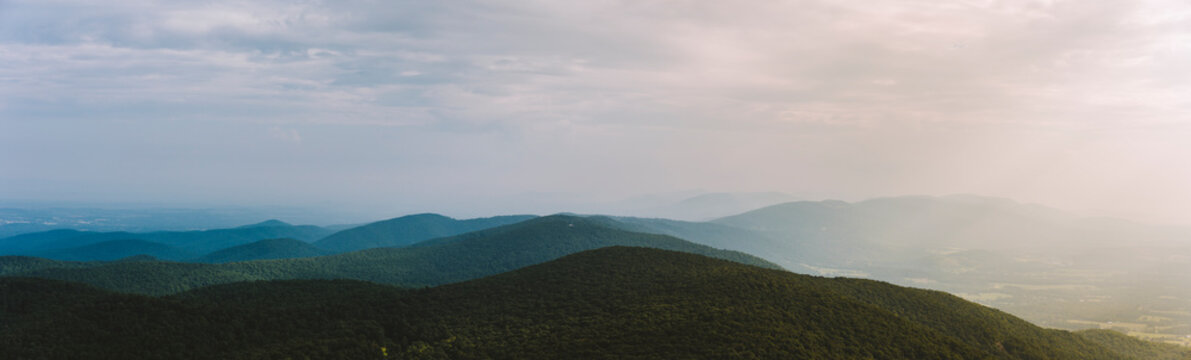 A panoramic view of a wide mountain range in Virginia with sun rays.