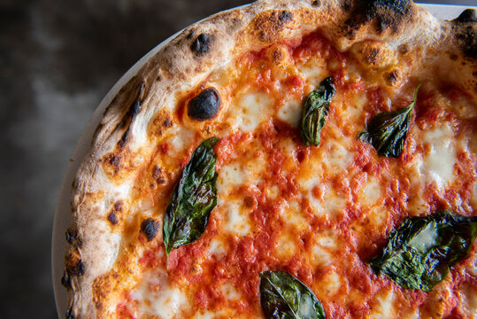 Close-up of thin-crust pizza with cheese, tomato and basilic