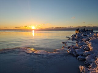 Winter Baltic sea and ice covered frozen breakwaters at dawn. Baltic sea - sandy winter beach with frozen breakwaters, white foam, waves on sunset. Scenic landscape Baltic sea in polar winter