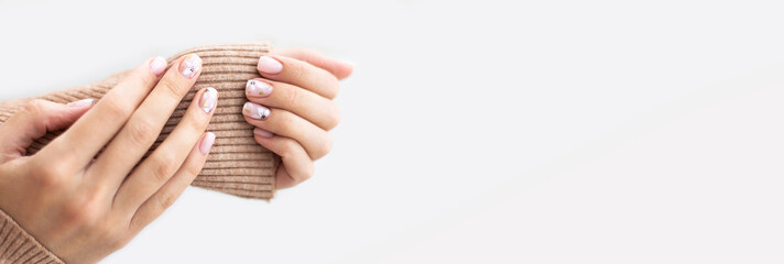 Pastel beige manicure on the light background. Manicured nails and soft hands skin salon banner...