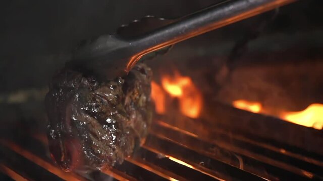 Chateaubriand steak is turned over on the edge for further grilling in a restaurant