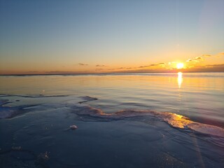 Snow covered ice floating in the frozen sea water at sunset