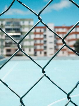 Close up of fence against blurred court and colorful buildings