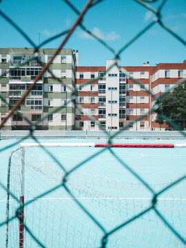 Blue court and colorful buildings through blurred fence