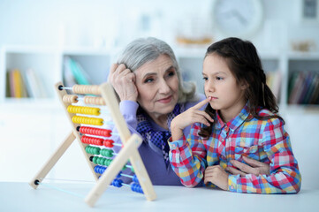Portrait of grandmother and granddaughter counting with abacus at home