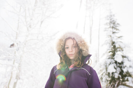 Low angle portrait of girl wearing warm clothing while standing against sky during winter