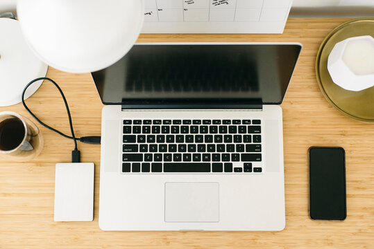 High angle view of laptop computer with mobile phone and hard drive on wooden table in office