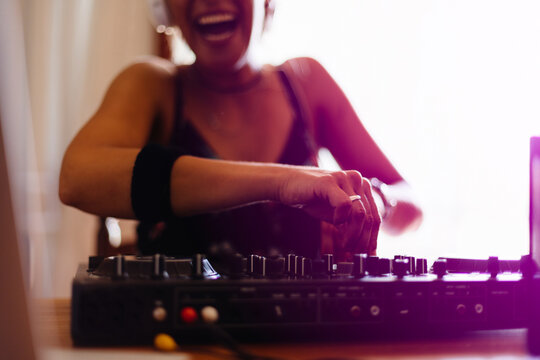 Midsection of happy female DJ mixing sound in recording studio