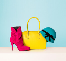 Woman fashion items. 
Yellow leather handbag, red boots and green hat.
