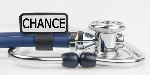 On the white surface lies a stethoscope with a plate with the inscription - CHANCE