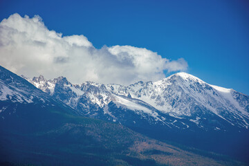 high tatra mountain ridge in springtime. cloud above the snow capped rocky peaks. beautiful sunny weather. wonderful nature scenery