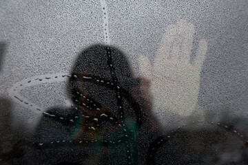Reflection of woman photographing hand on wet glass during monsoon