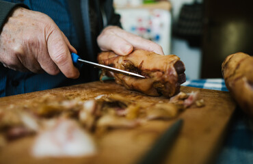 Close-up of men's hands cleaning pork legs with a knife, which are one of the ingredients for the traditional Serbian dish 