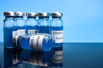 Coronavirus vaccine in ampoules on the mirror table. COVID-19 vaccination concept