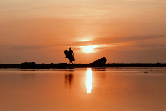 Silhouette of surfer at sunset on the beach