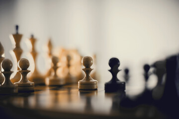 Two pawns - black and white. Wooden chess pieces on the chessboard.