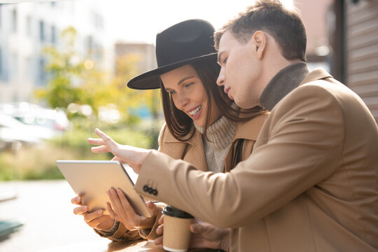 Young couple in stylish casualwear resting in outdoor cafe and using tablet - Powered by Adobe