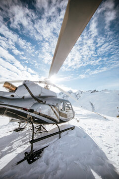 Helicopter landed on snow covered mountain.